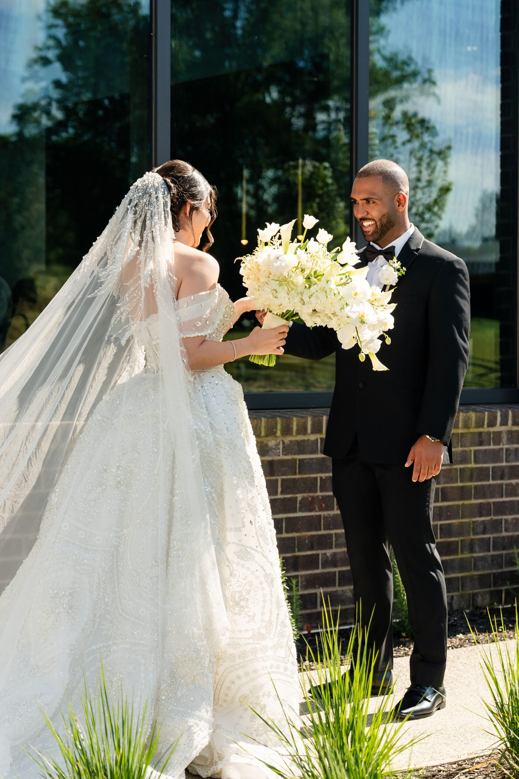 A bride and groom sharing a first look outside of the Lumen House glasshouse venue in North Carolina.