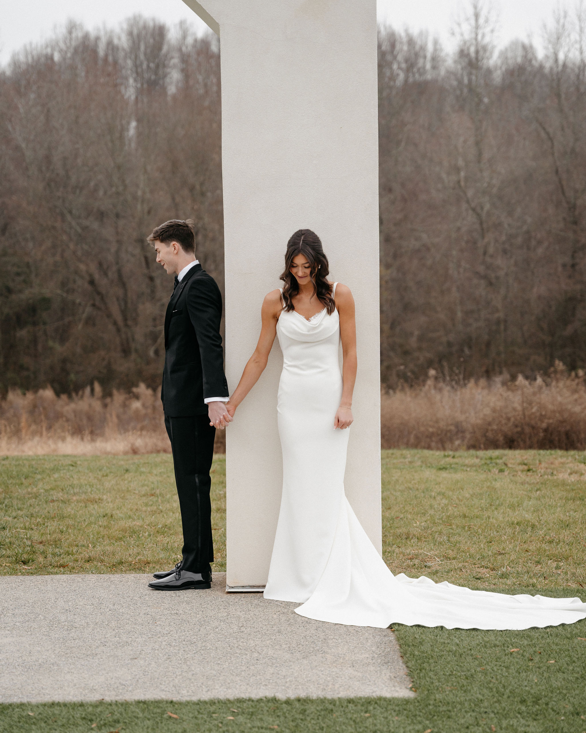 A bride and groom sharing a first touch moment beneath a modern wedding venue arch.