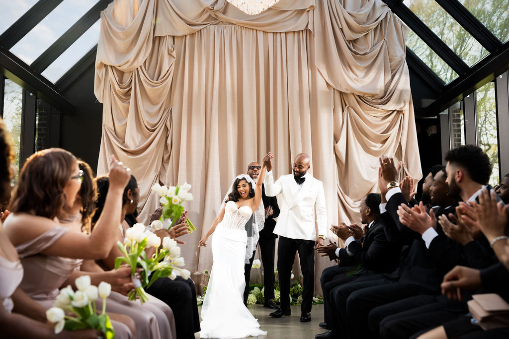 A bride and groom celebrate as newlyweds as they make their way back down the aisle.