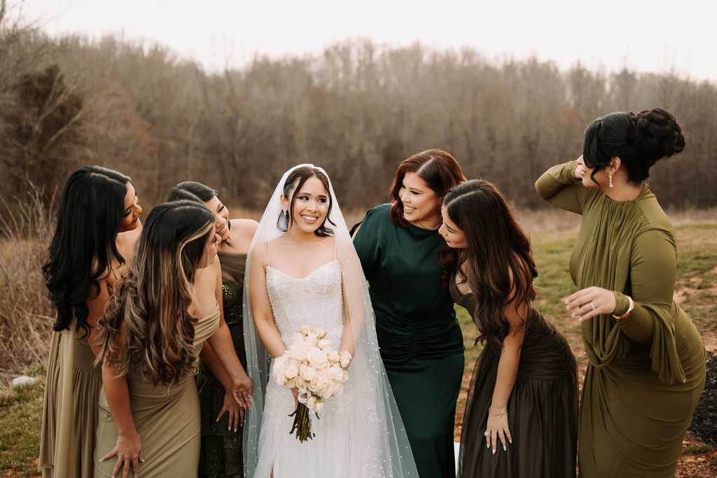 A bride poses with her bridesmaids in jewel-tone dresses.